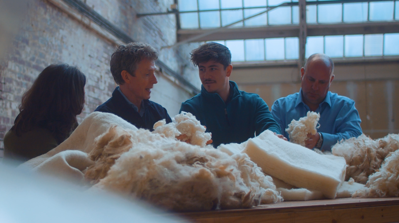 Close up image of 3 men and 1 woman working in a factory, organising the wool that will go into a Hypnos Beds mattress