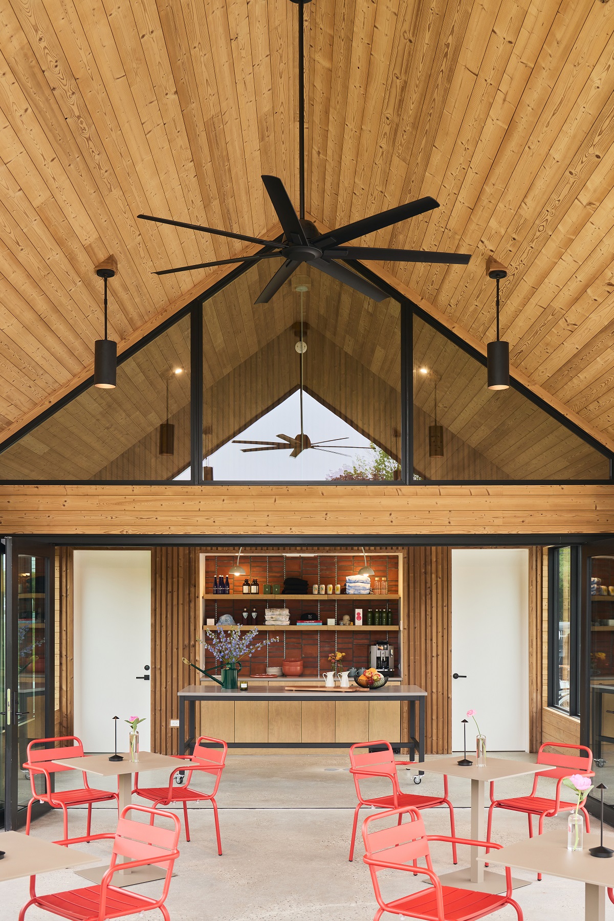open wooden panelled a-frame ceiling with orange bistrot chairs and tables in Three Ducks Hotel