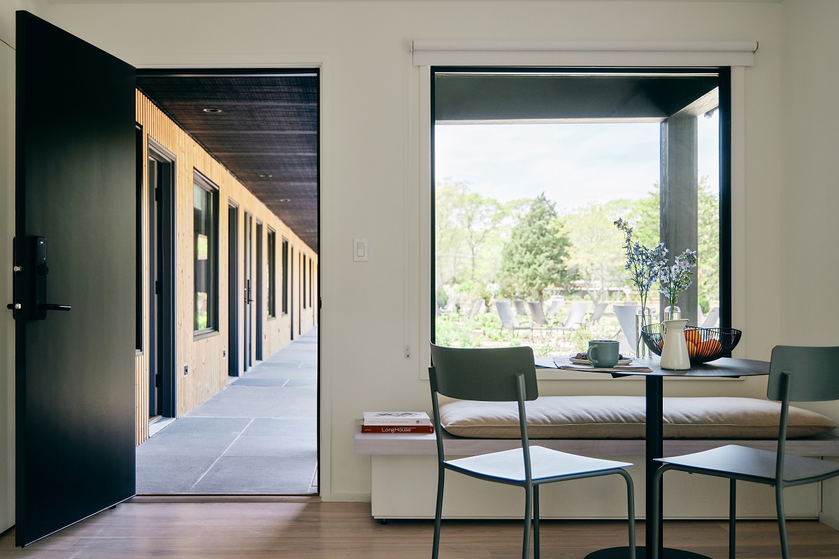 chair and table in front of window with door opening on to outdoor corridor