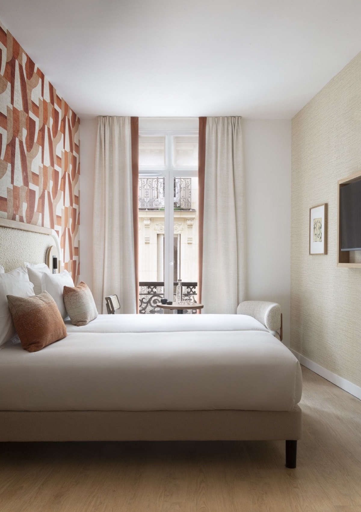 bedroom with floor to ceiling window and parisian balcony with arte wallpaper behind the bed