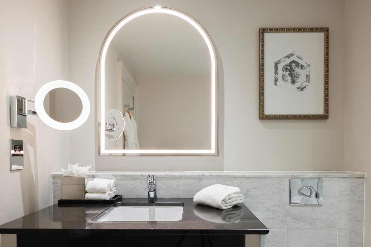hotel bathroom with arched backlit mirror above vanity