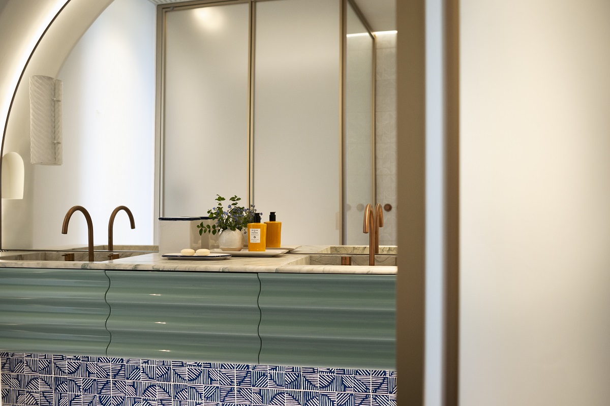 teal green rippled vanity with blue patterned tiles in arched bathroom alcove