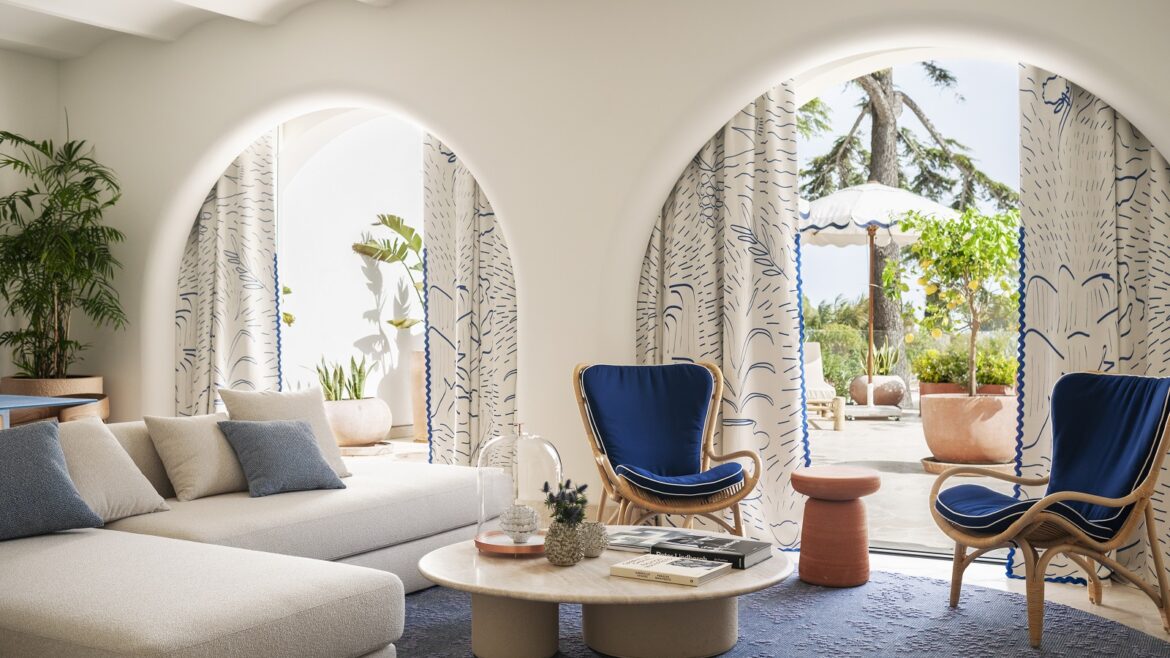 table and sofa in front of arched doors leading onto terrace and pool at Jumeirah Capri Palace