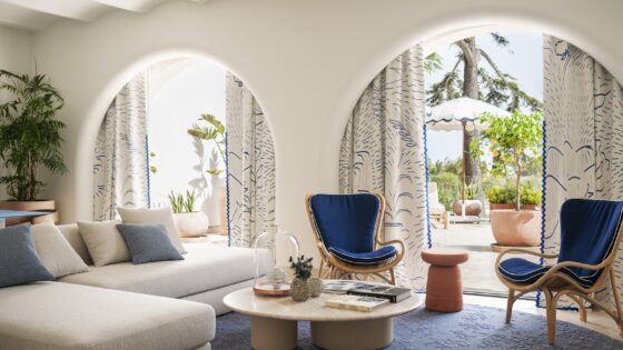 table and sofa in front of arched doors leading onto terrace and pool at Jumeirah Capri Palace