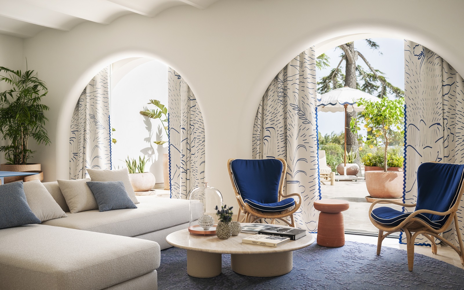 table and sofa in front of arched doors leading onto terrace and pool at Jumeirah Capri Palace