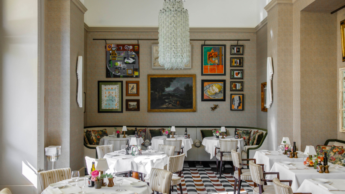 Restaurant space at Hotel Savoy, with brightly coloured gallery wall and large glass chandelier