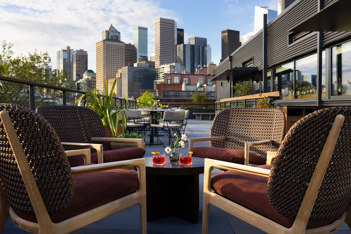 wooden chairs and cocktail in front of city view from rooftop