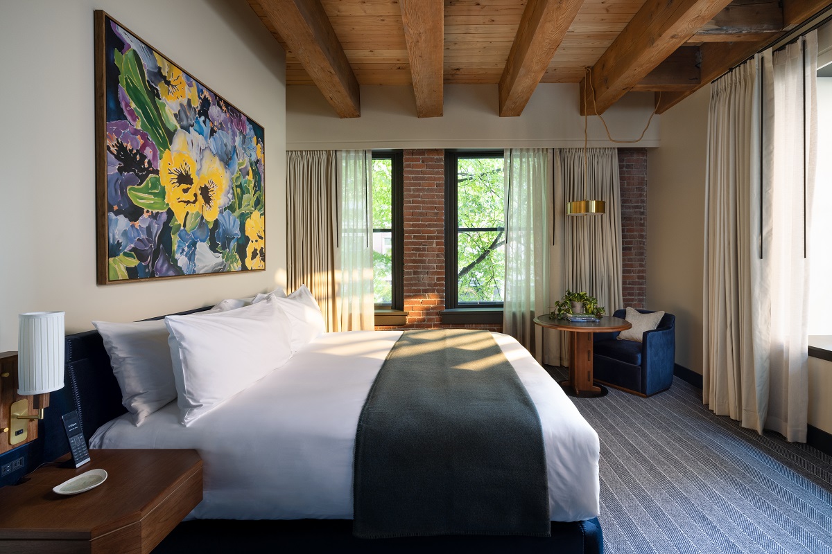 double bed with art above, wooden beams and floors in Populus Seattle