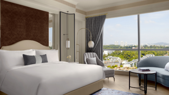 double bed and sofa in front of floor to ceiling window overlooking Singapore in The St Regis