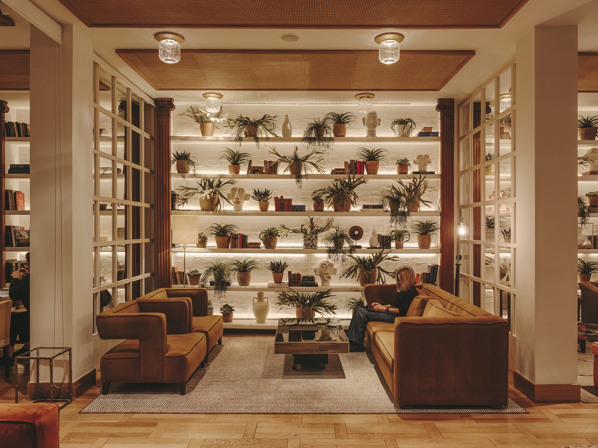 facing brown sofas in front of wall with shelves and plants