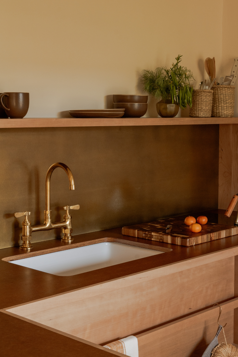 Kitchenette in neutral tones with white sink and gold taps by Manola Studio