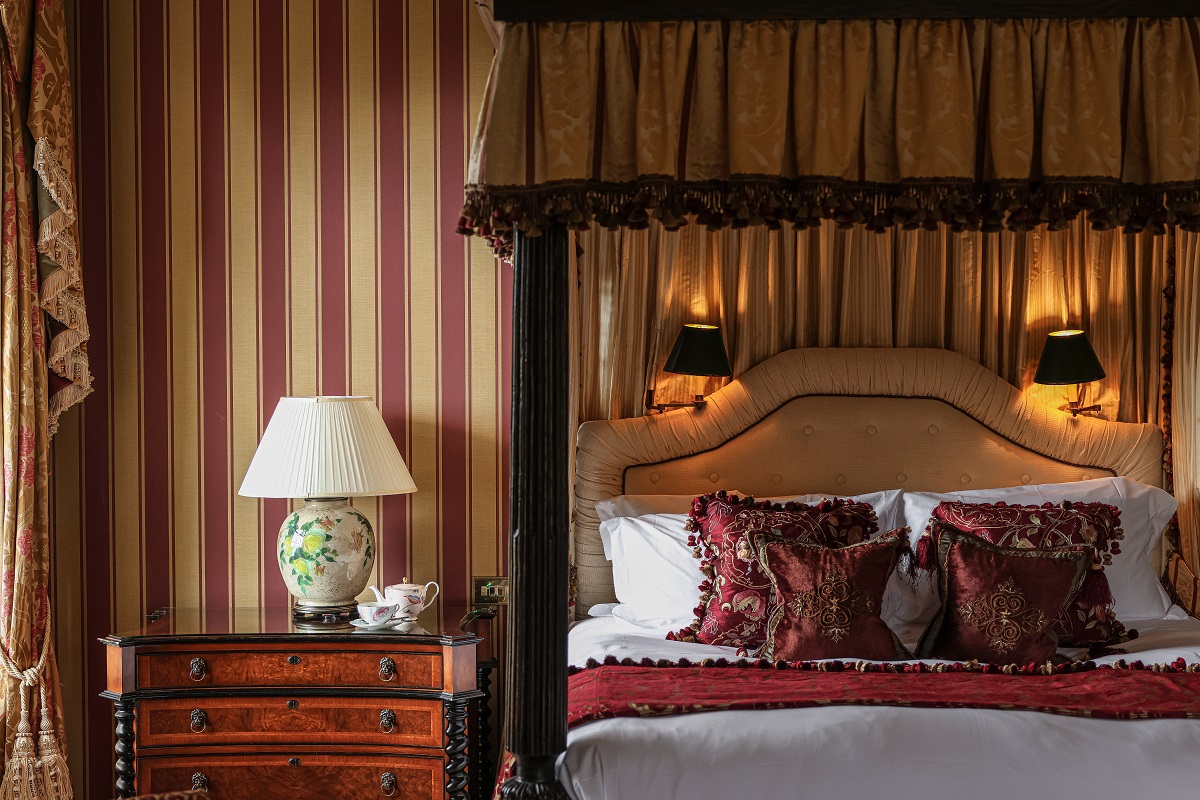 detail of period bed , wooden furniture and striped wallpaper