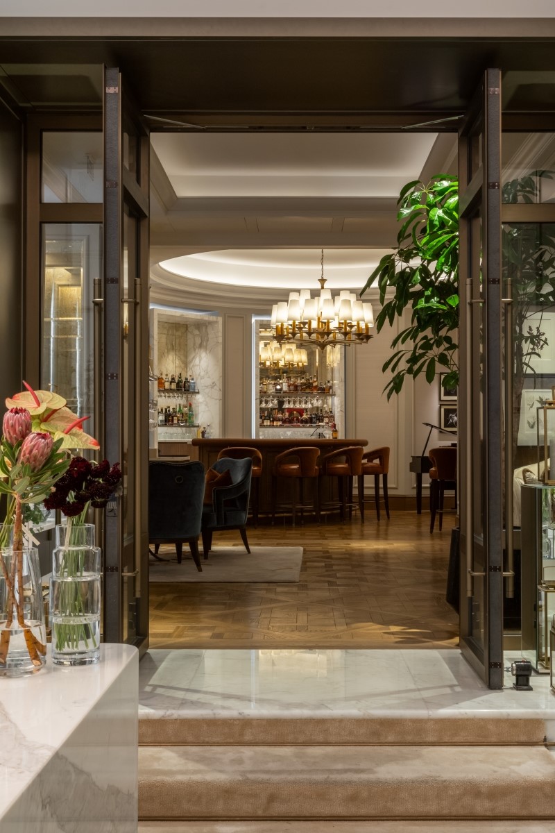 Glass entranceway to the Heritage Bar at the Corinthia Bucharest, with marble steps leading into room