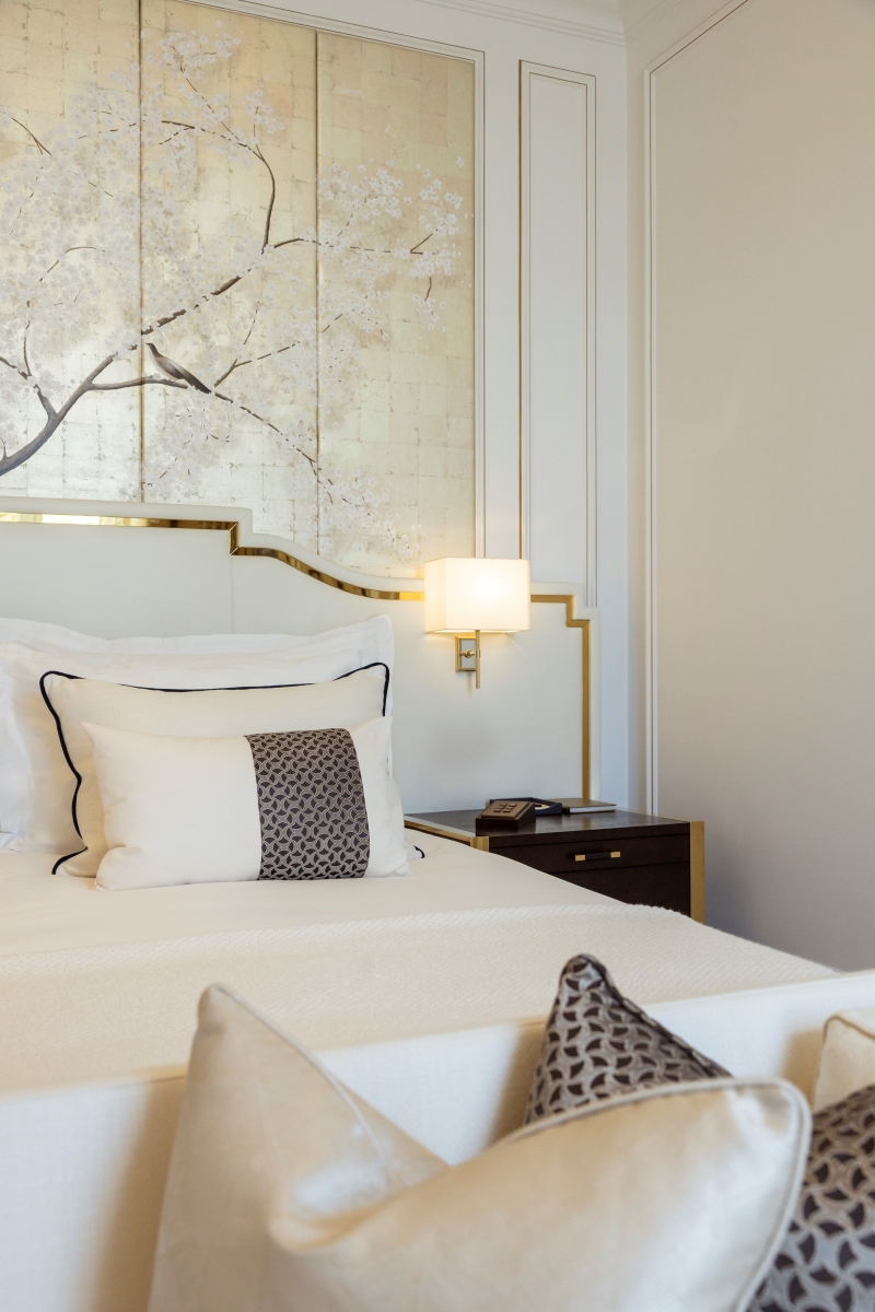 Shot of bedroom at Corinthia Grand Hotel Bucharest, designed by GA Group. Far wall shows gold print with white cherry blossom flowers covering.