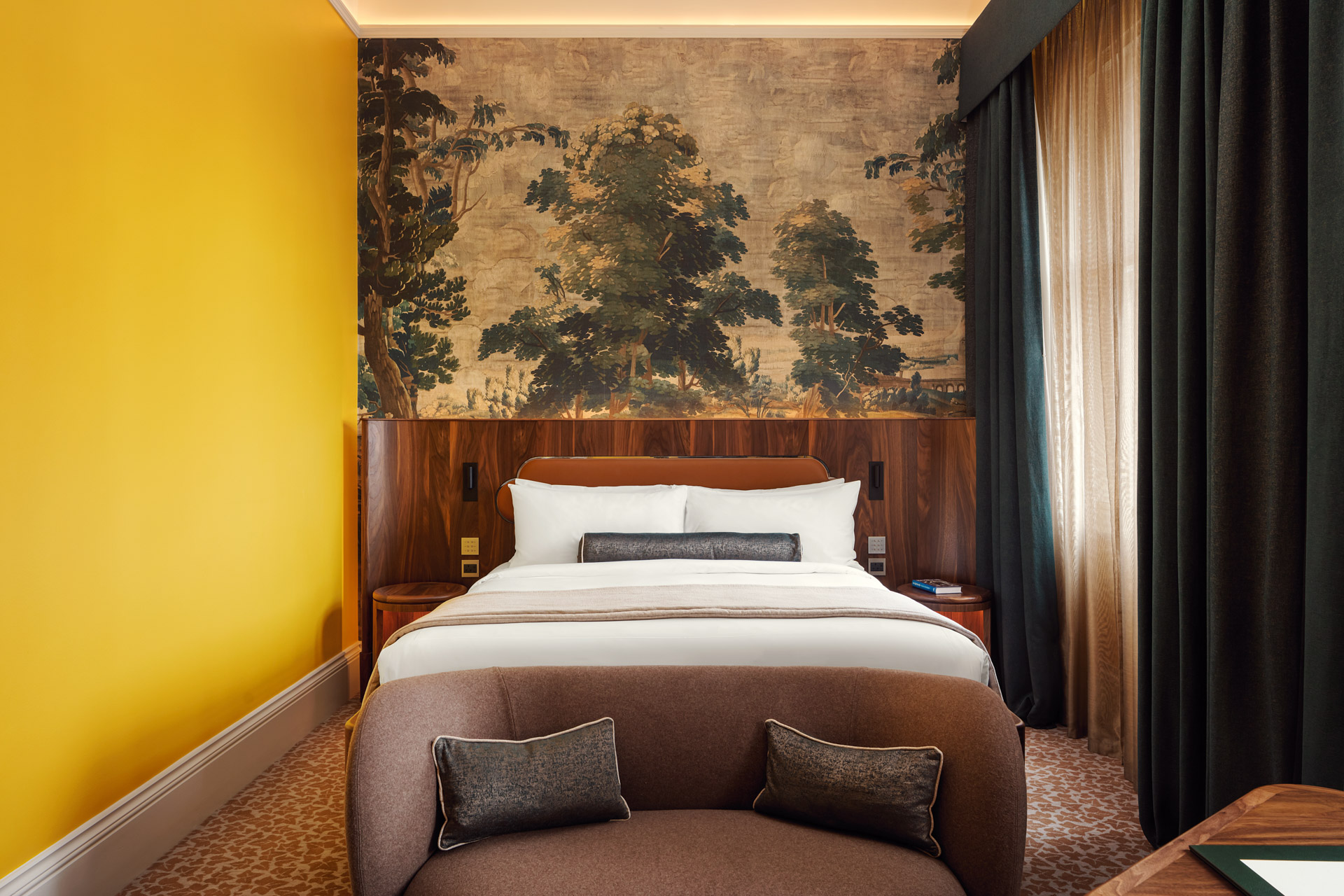 yellow wall with mural behind wooden bedhead in guestroom St Pancras hotel