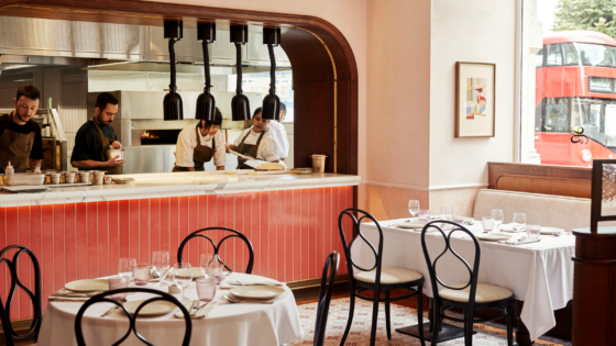 Leydi restaurant at Hyde Hotel London, with pink tiled open kitchen and french bistro style chairs around round tables with white table cloth
