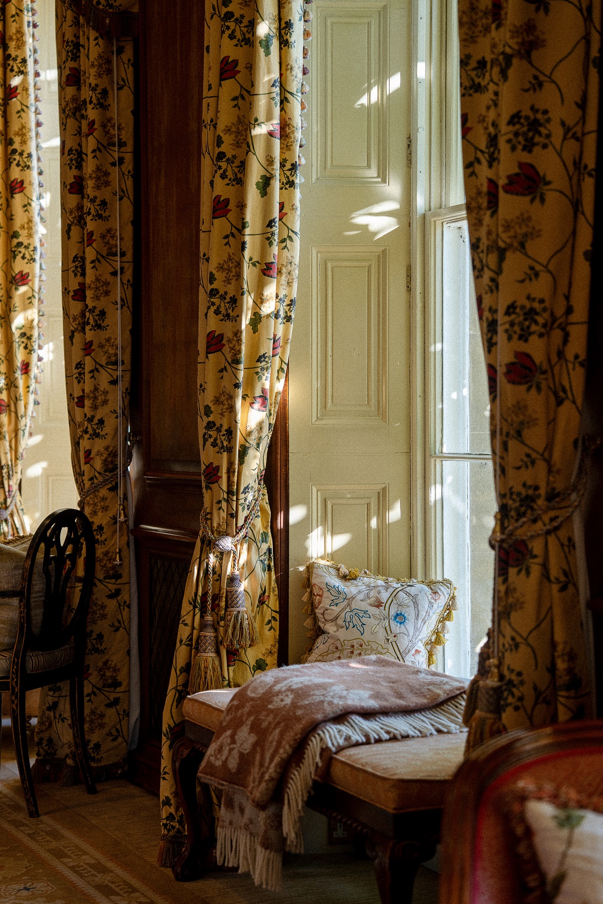 window seat with brocade curtains and dappled light