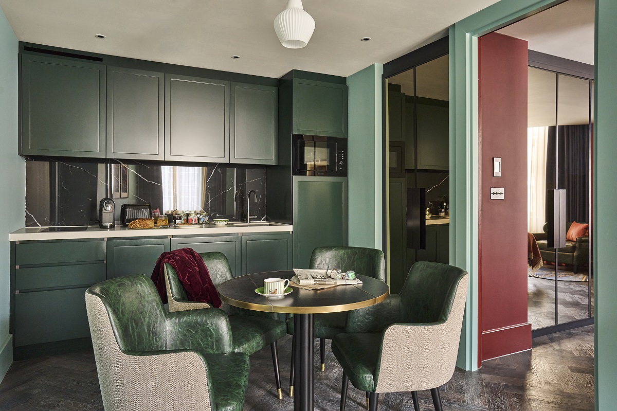 dining table with green leather chairs in dark green kitchenette
