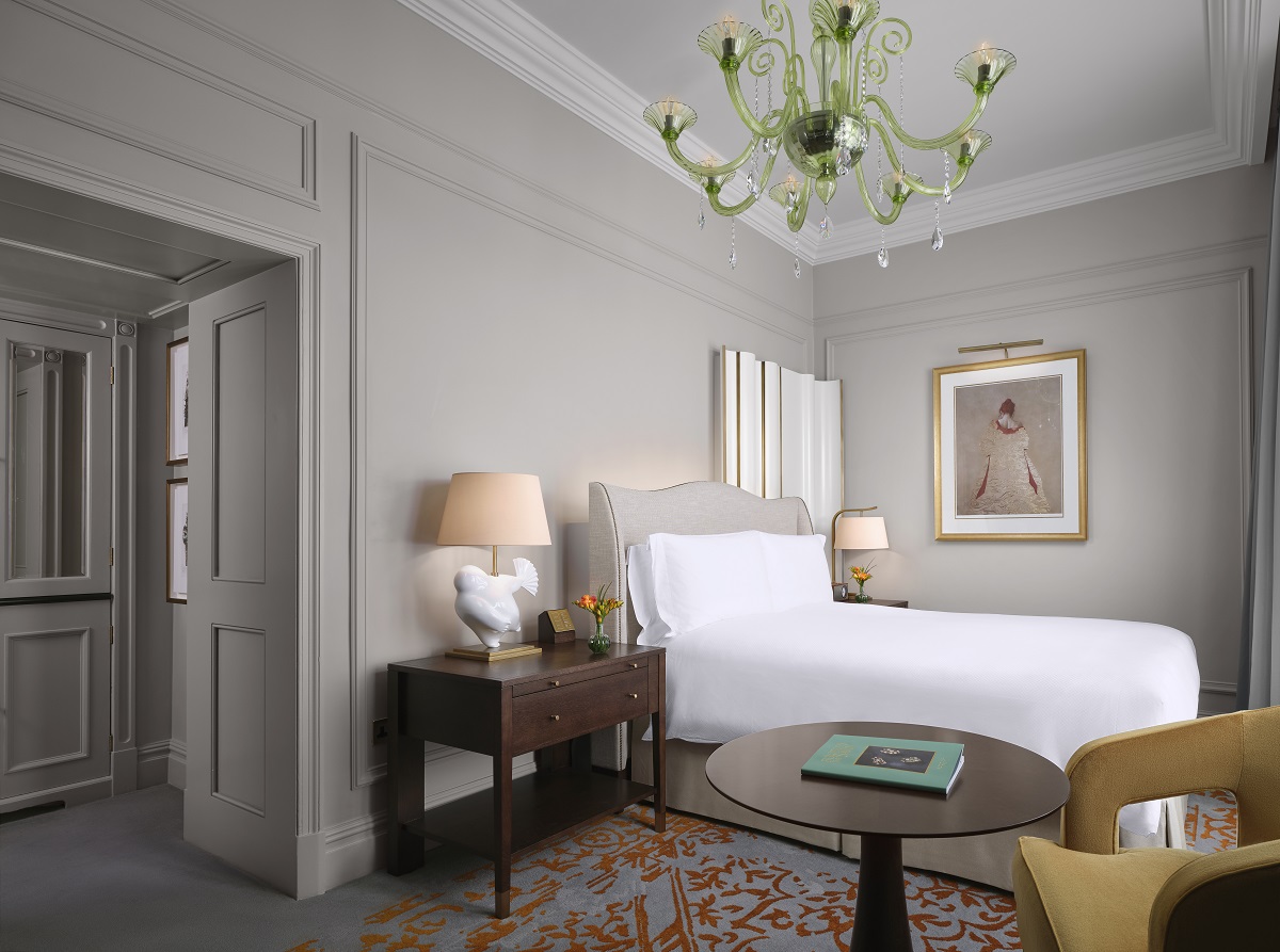 glass chandelier above white linen on double bed in suite with grey walls