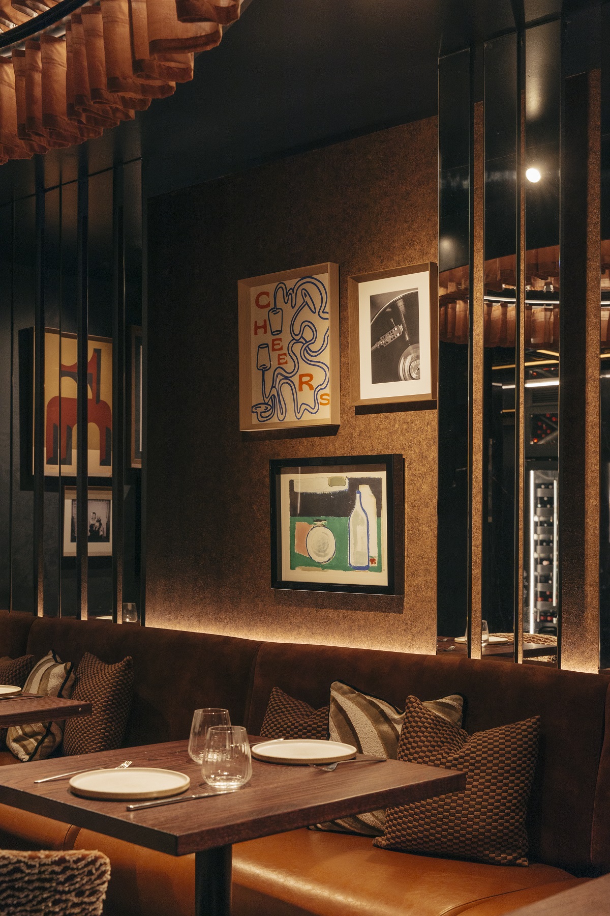 table and banquette in corner of Roostiq Bar with art on the wall