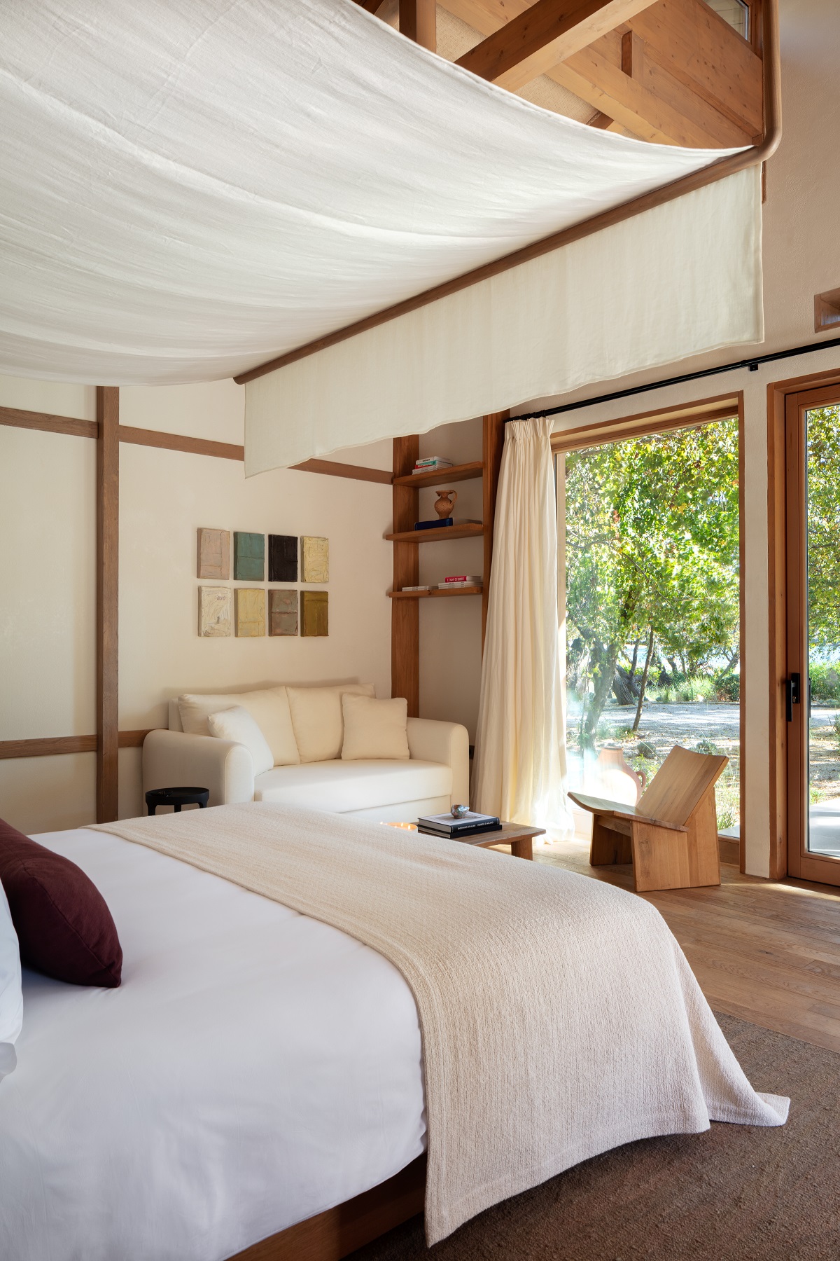 bedroom in cabin with white linen on bed and white draped canopy above the bed