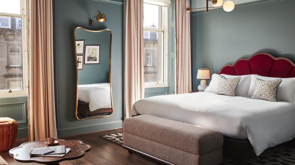 blue guestroom walls, red headboard and period sash windows in Hoxton Edinburgh