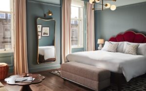 blue guestroom walls, red headboard and period sash windows in Hoxton Edinburgh