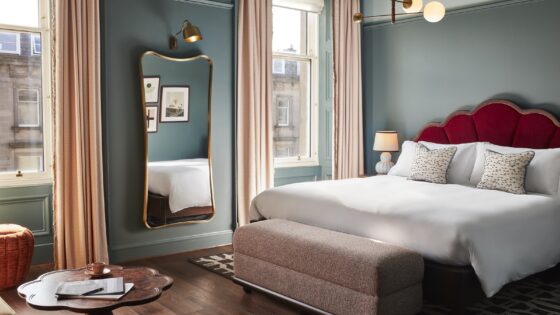 blue guestroom walls, red headboard and period sash windows in Hoxton Edinburgh