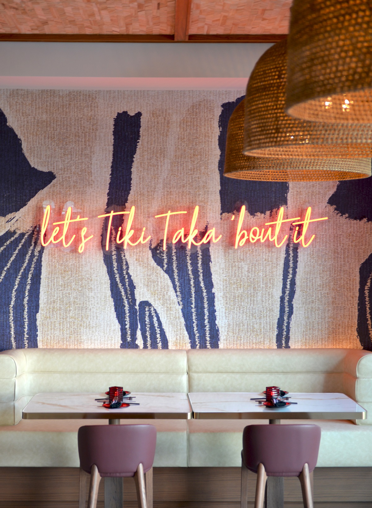 taupe chairs facing cream banquette in front of neon sign in restaurant