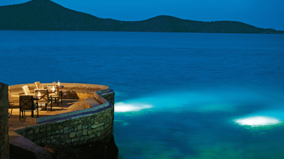 Sumosan restaurant at Elounda Collection, curved stone jetty looks out across ocean at night