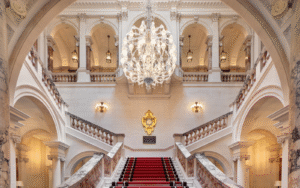 Great chandelier hangs above marble staircase at The OWO, lighting by Lutron
