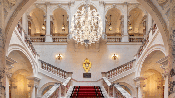 Great chandelier hangs above marble staircase at The OWO, lighting by Lutron