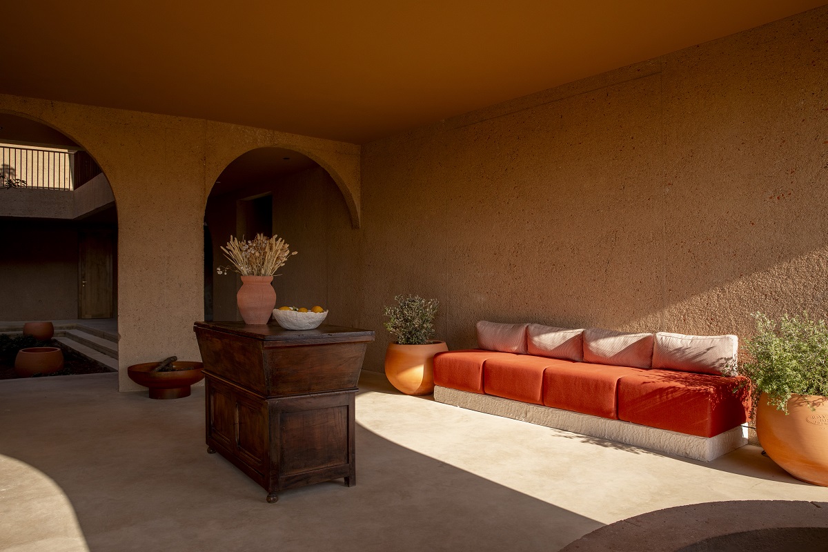 natural concrete walls and burnt orange sofa in sunshine on the terrace at Mylos Hotel