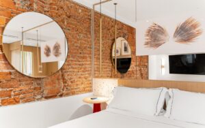 round mirror on exposed brick wall in hotel guestroom