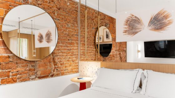 round mirror on exposed brick wall in hotel guestroom
