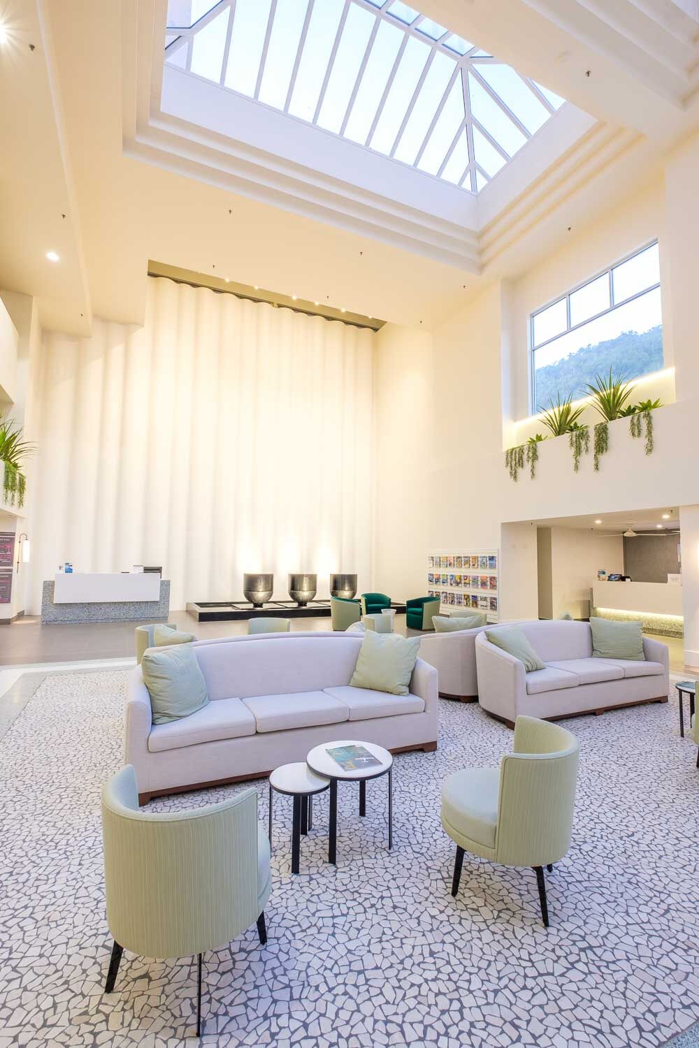 View of white Corian curtain wall with sofas infront and glass ceiling above