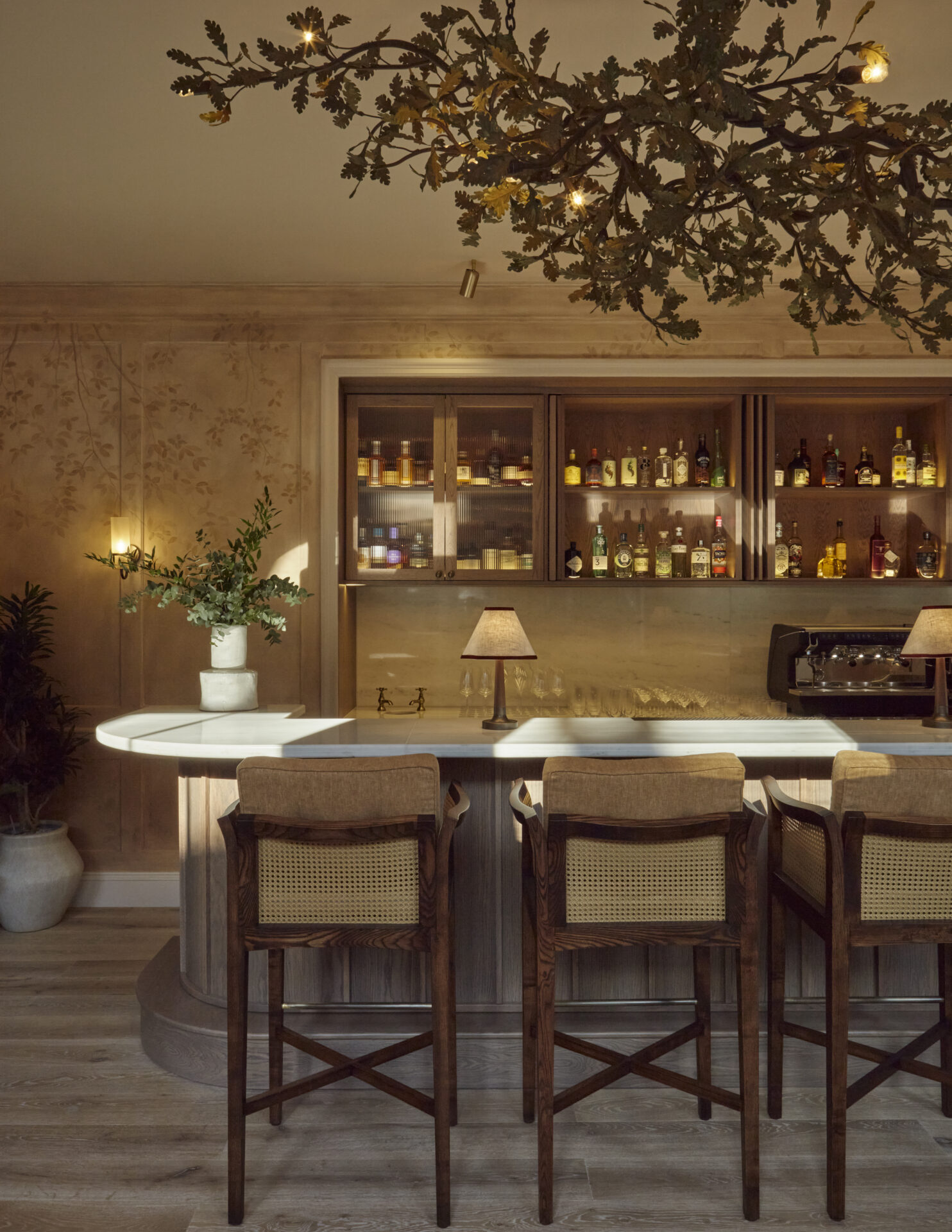 Sprout bar features a oak tree-inspired chandelier and handpaint wall mural in terracotta tones