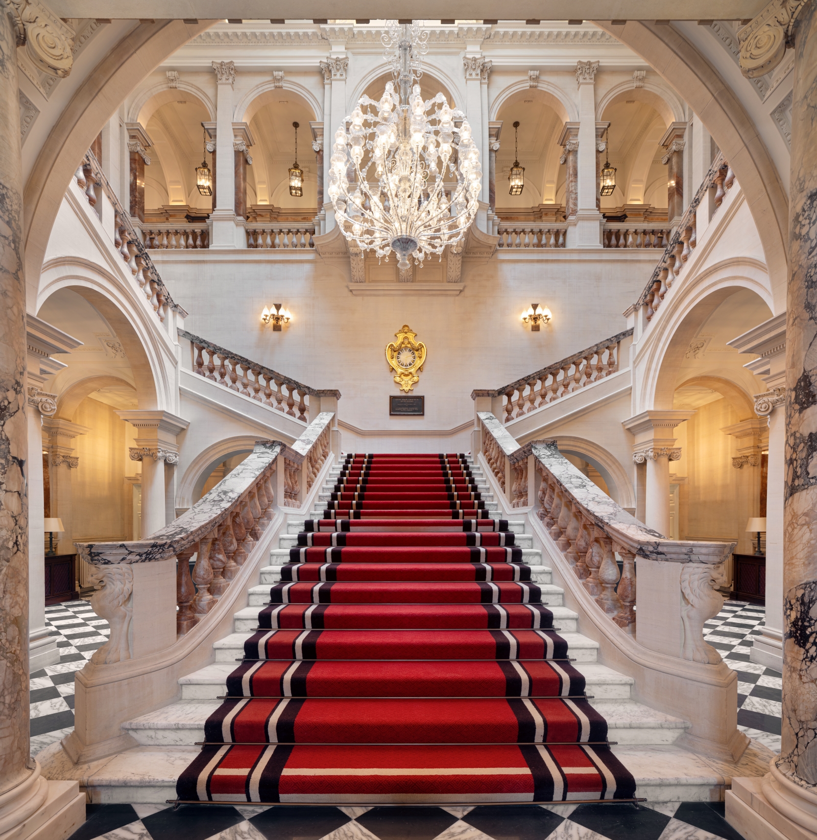Great chandelier hangs above marble staircase at The OWO, lighting by Lutron