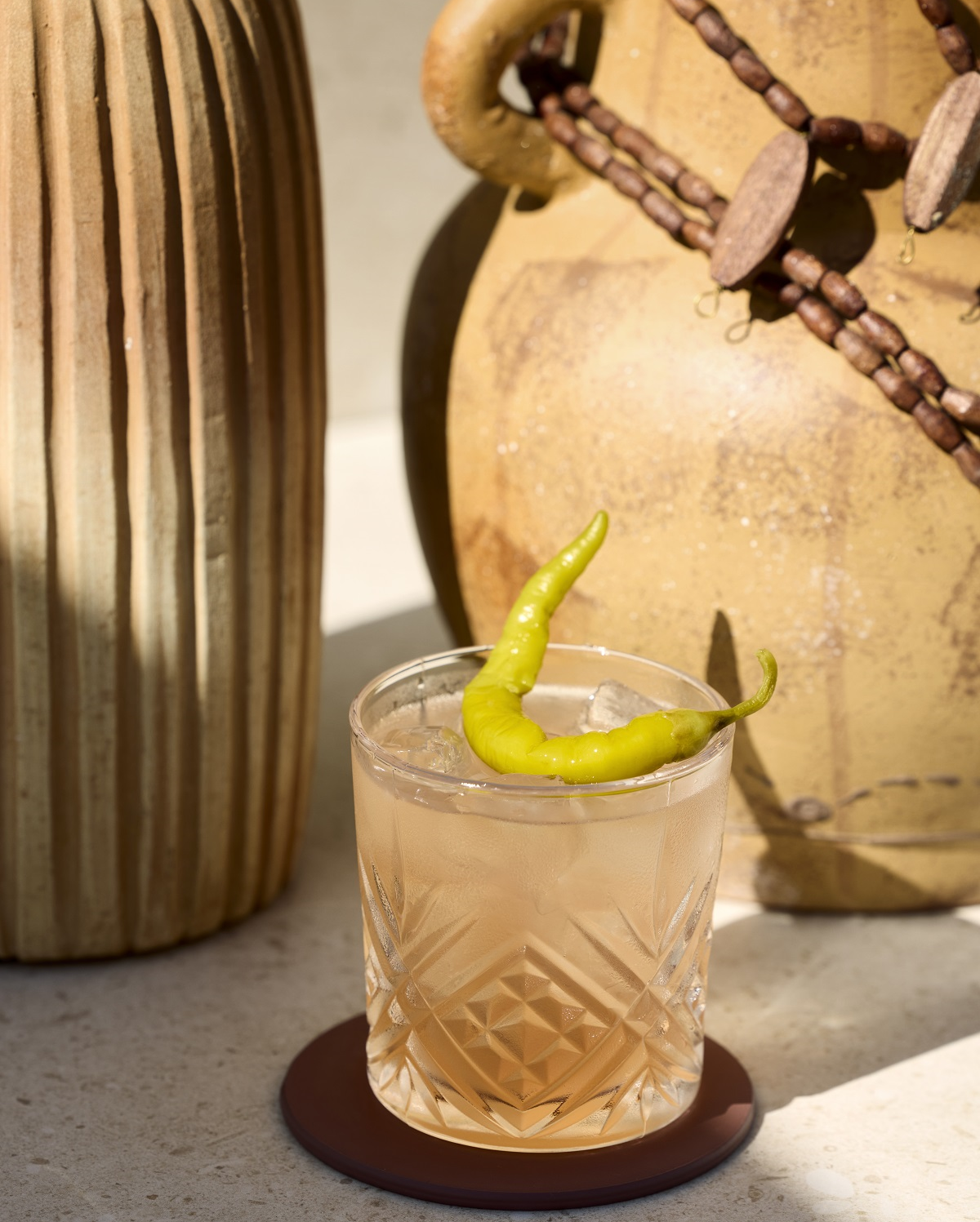 cocktail with chilli garnish with clay pots in background