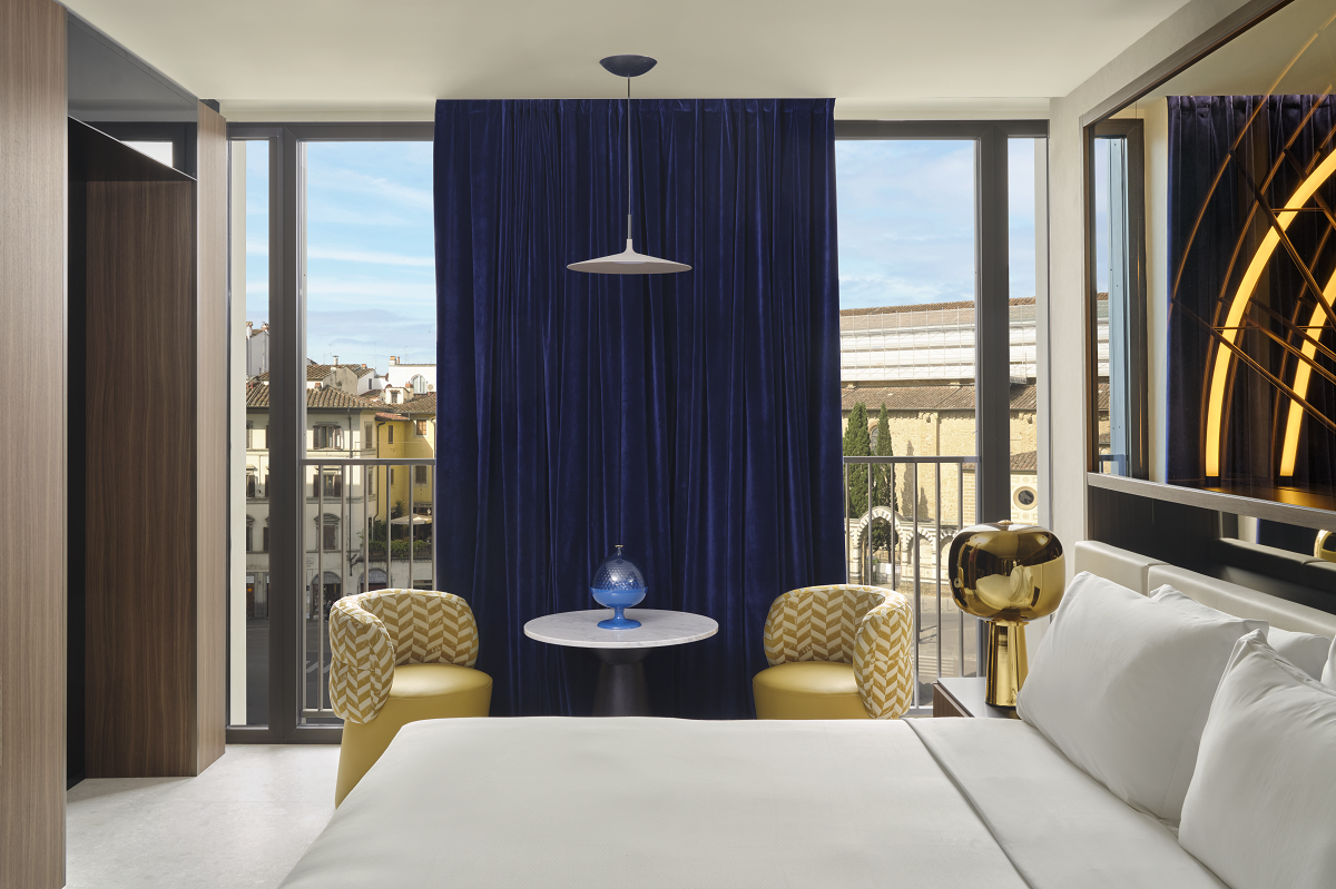 W Florence guestroom with blue curtains in floor to ceiling window with view over florence