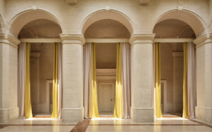3 arches in cream stone framed with yellow floor to ceiling curtains in Vista Ostuni - a five-star luxury hotel and part of the Vista brand