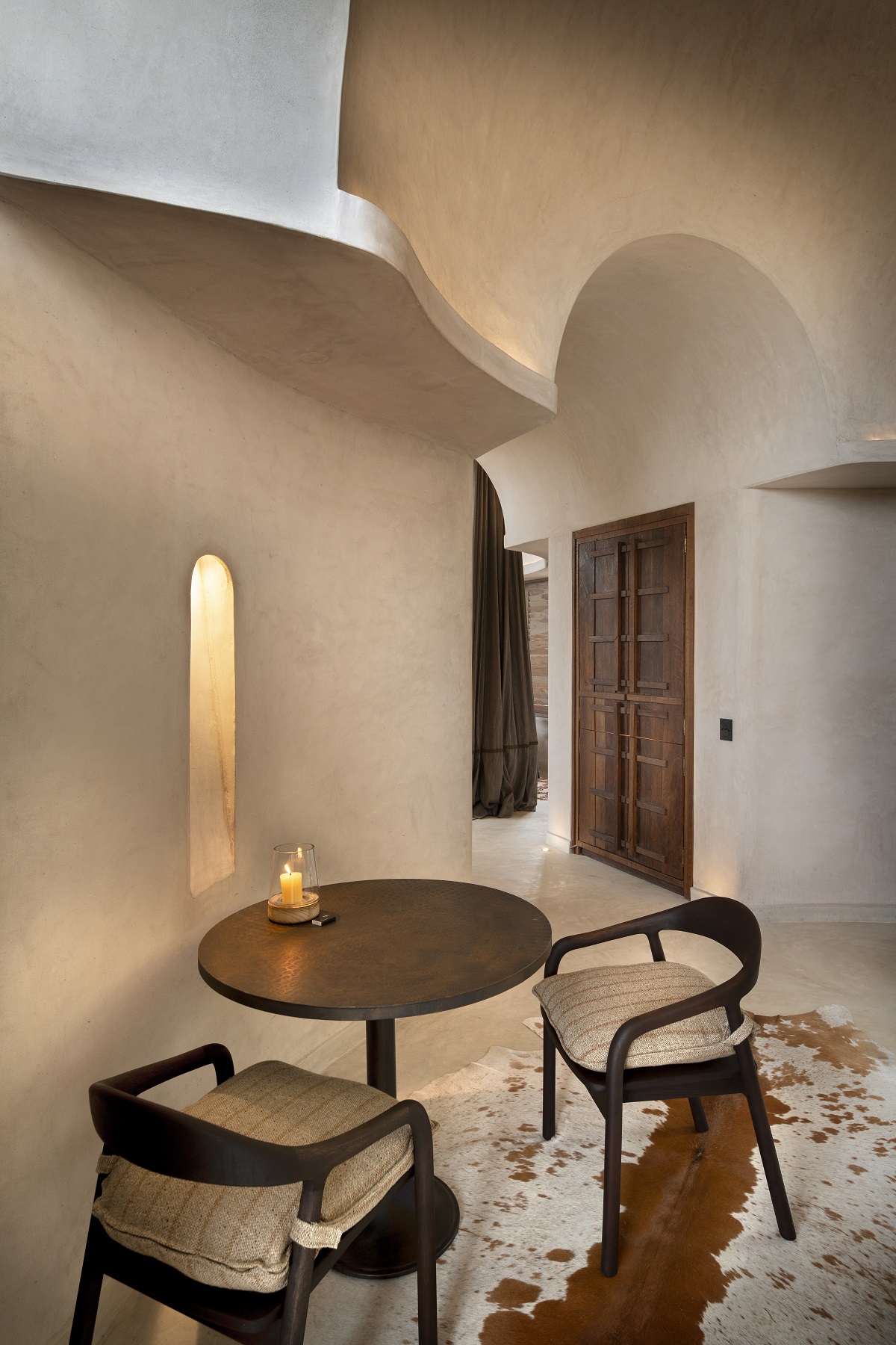 table and chair on animal skin mat below curved architectural detail in Suyian Lodge