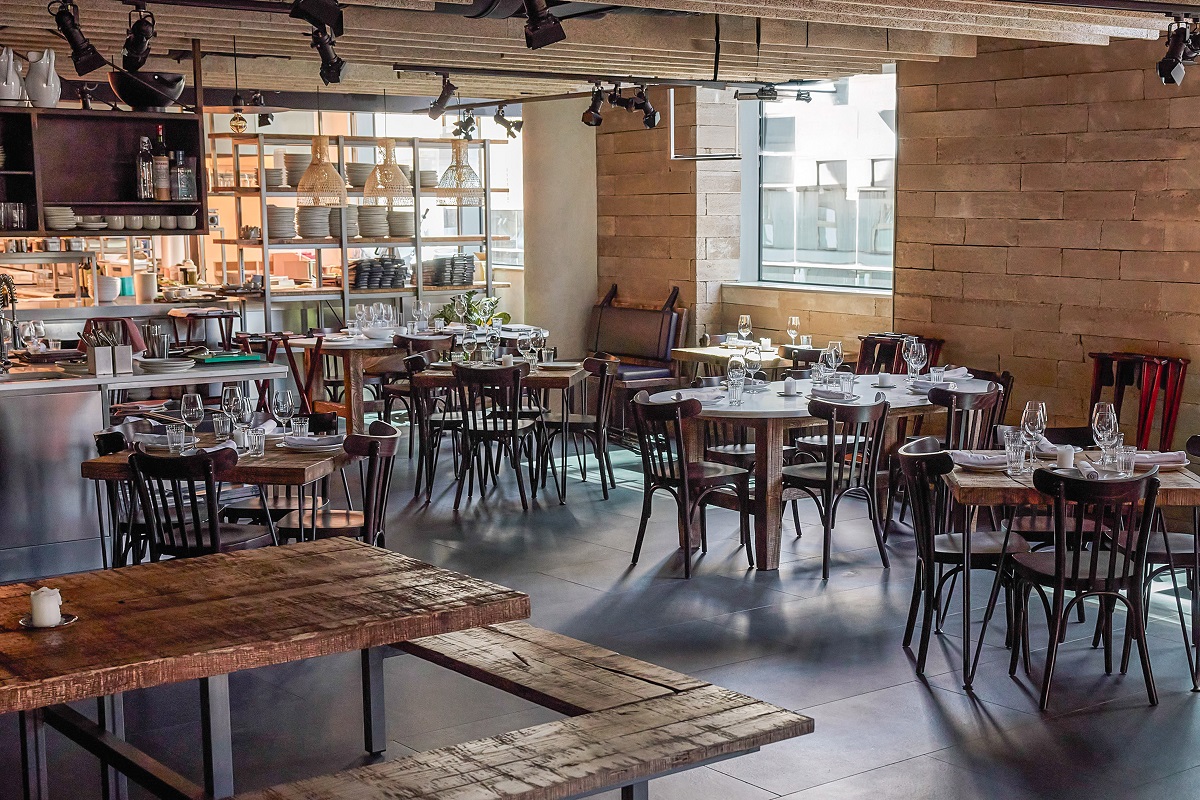 tables and chairs on concrete floor with exposed brick walls in Me Lisbon-Fismuler Restaurant