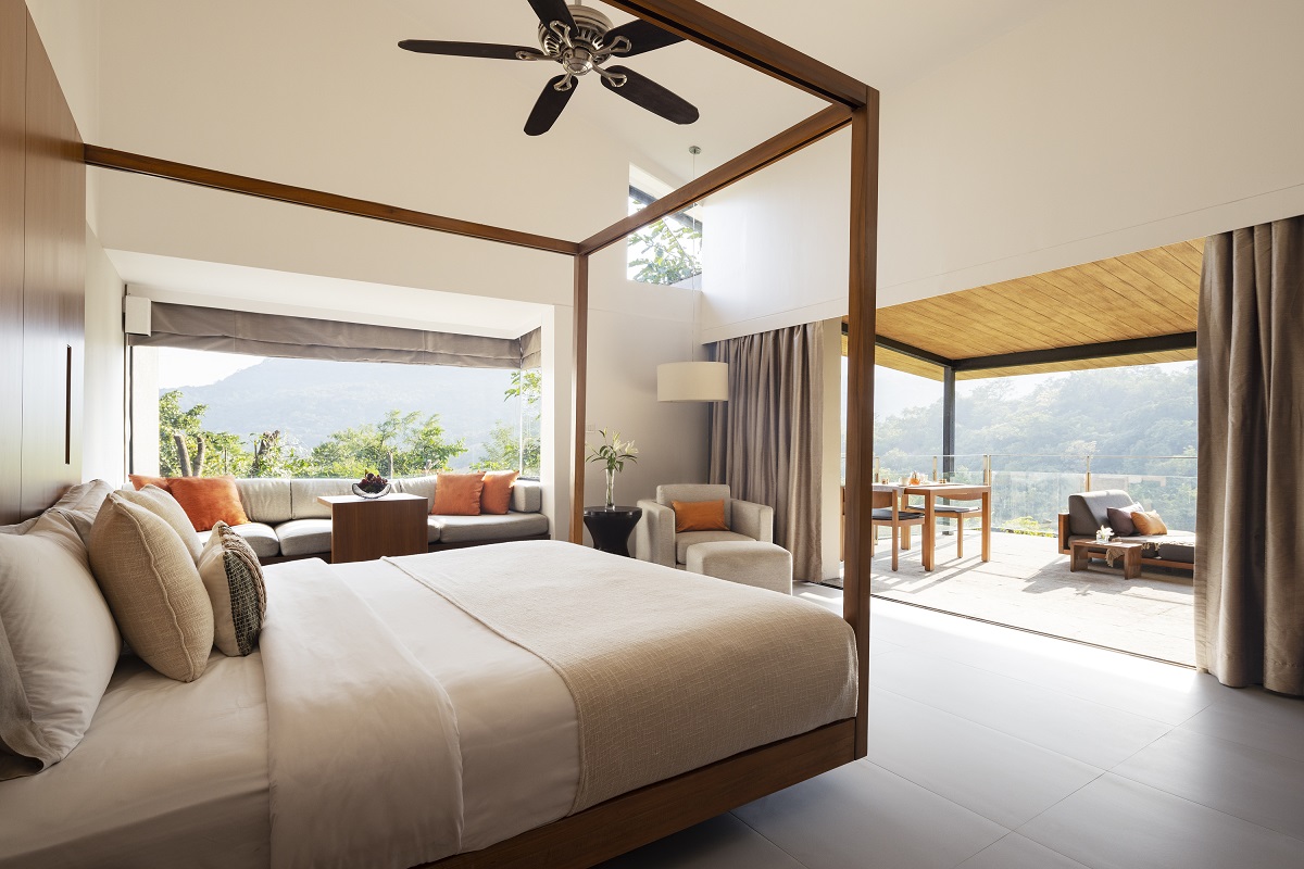 bedroom in hillside villa with minimalist wooden four poster bed and views across landscape