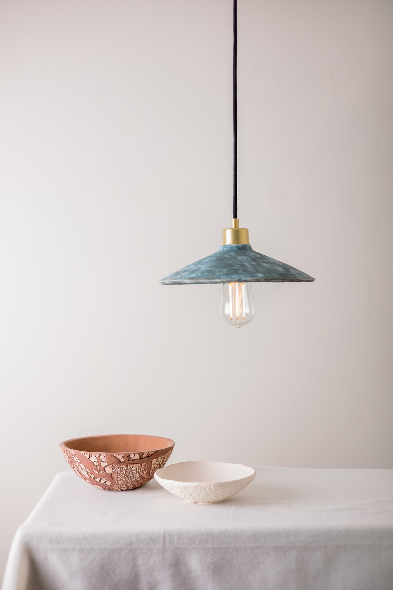 Ceramic light fitting hanging above two ceramic bowls on white table