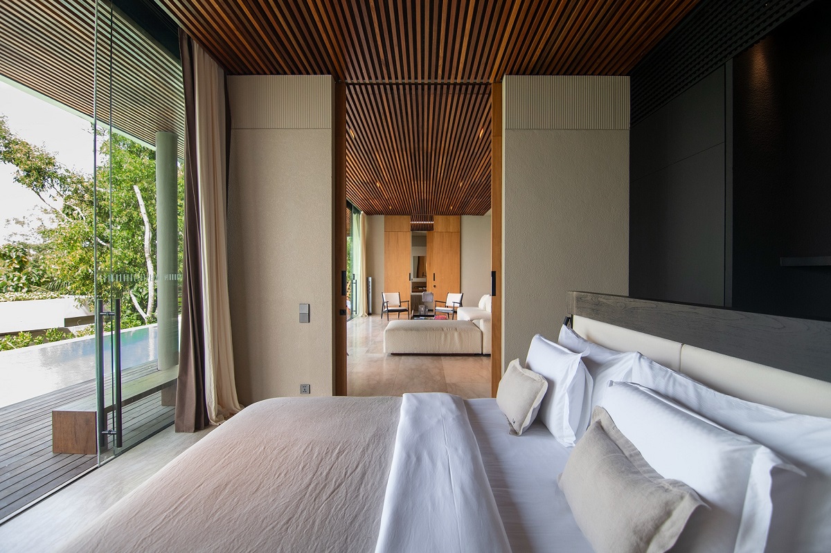 double bed with view through lounge area and glass doors onto pool