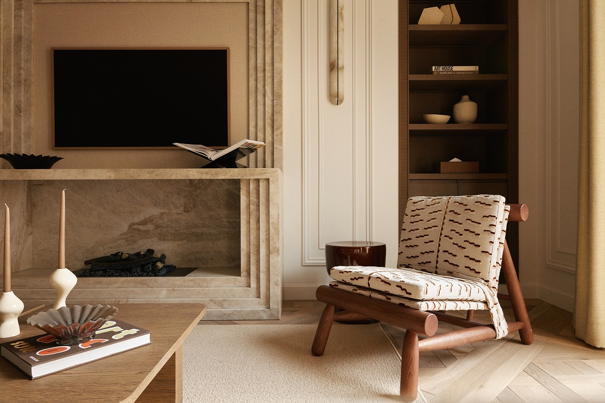 wooden armchair with cushions in front of fire place and table in minimalist Parisian apartment