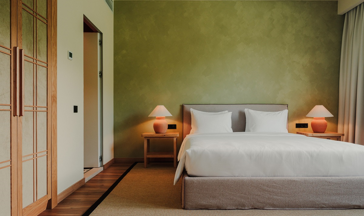 hotel guestroom with pistachio green wall behind the bed 
