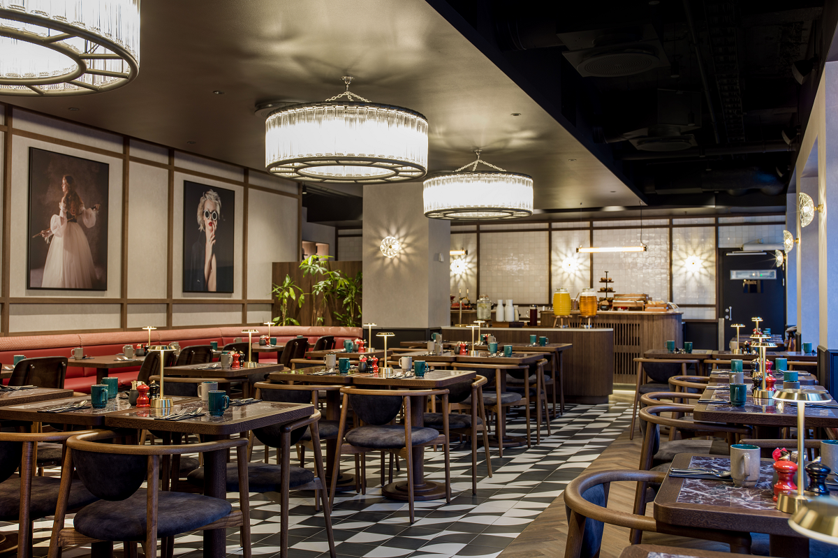 black and white checked floor, wooden tables and chairs, art on walls in restaurant of Radisson RED Oslo