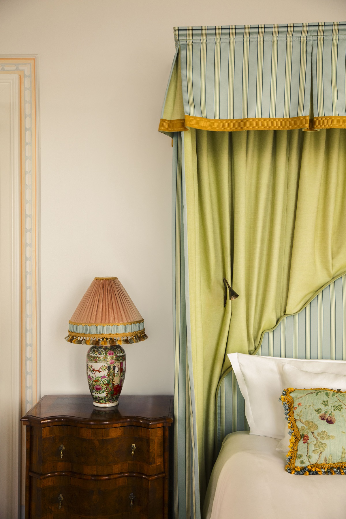 bedside table, lamp, bed and canopy detail in Villa Beatrice designed by Martin Brudnizki